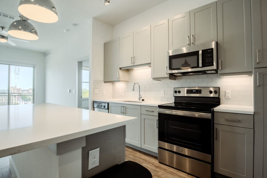 Studio Apartments In Downtown San Antonio, TX - Augusta Flats - Kitchen With Stainless Steel High Efficiency Appliances, Quartz Countertops, Two Tone Cabinet Finishes And Plank Flooring.